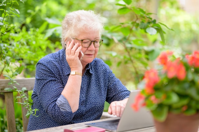 senior woman on phone whilst using laptop