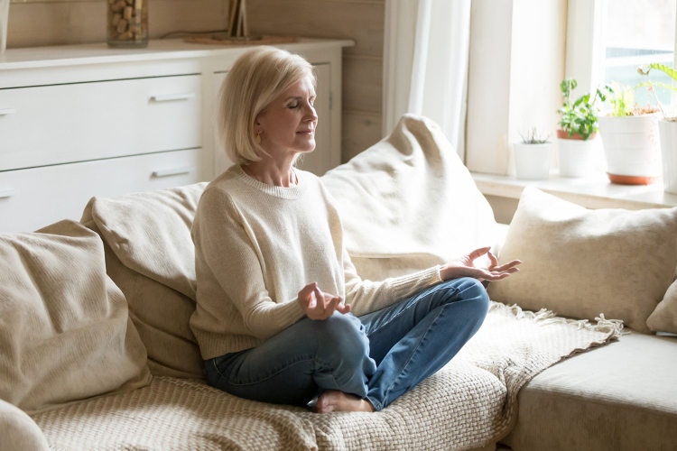 A senior women meditating on a couch
