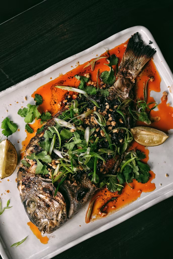fish dish covered in herbs and orange sauce