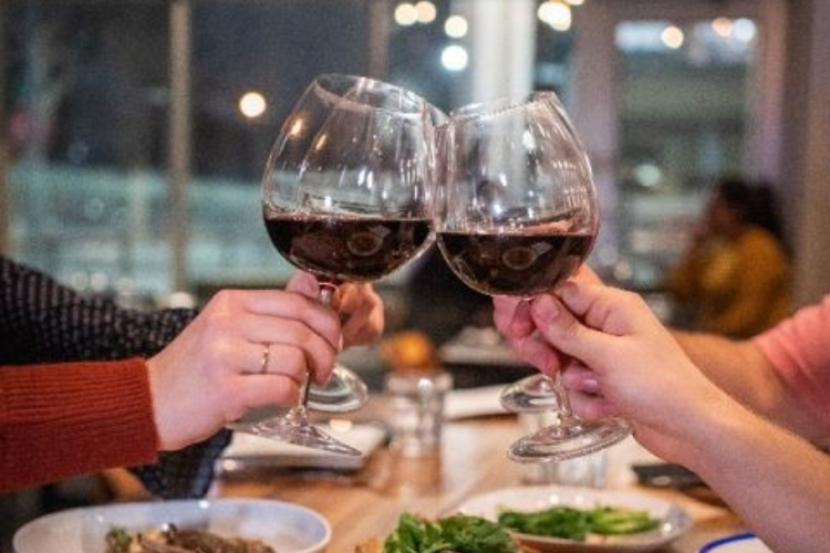 Group of 4 in a restaurant clinking wine glasses