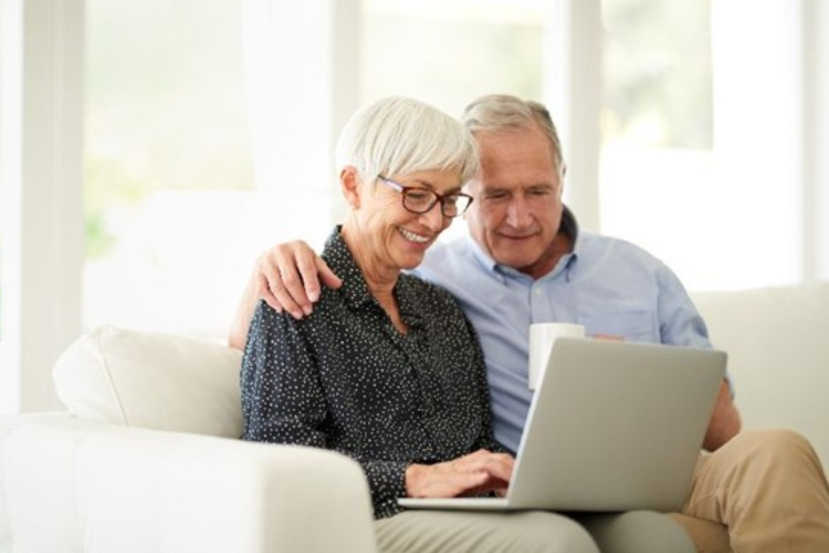 Senior couple sat together looking at a laptop