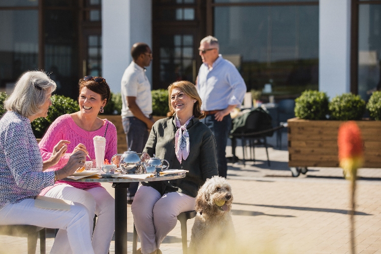 Senior women outside drinking coffee with a dog